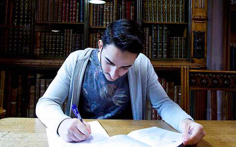 Student writing in a dark John Rylands Library space