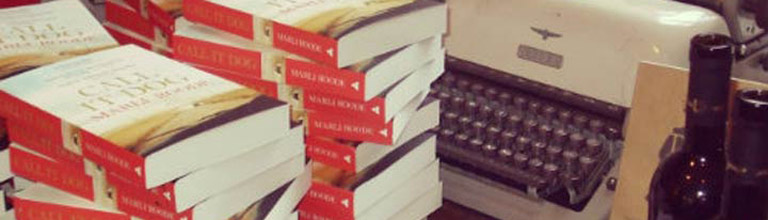 Pile of books on a desk with a typewriter
