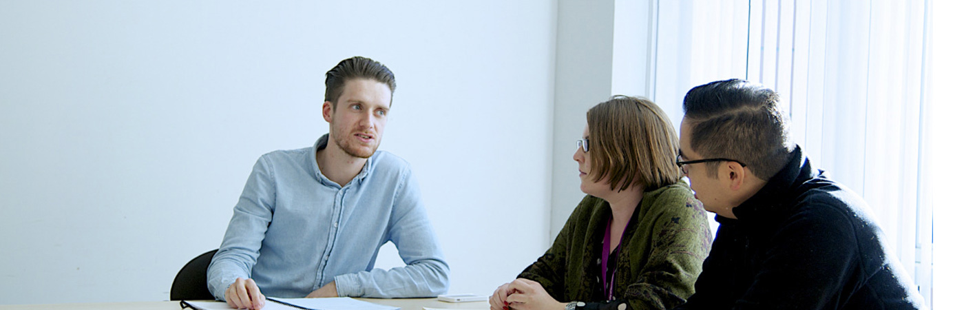 Man talking to two people sat at table